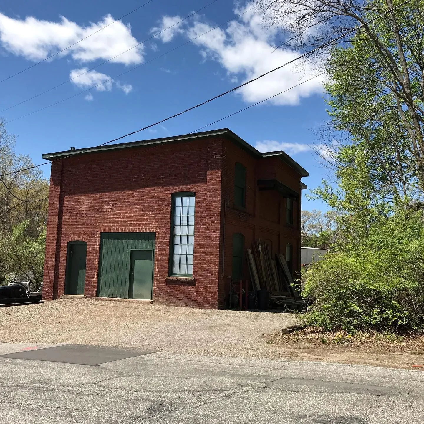 Two-story red brick outbuilding with tall arched windows and a green door