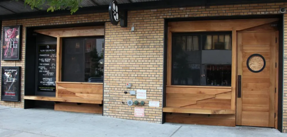 Brick storefront with timber window seats and a wood door with a round window