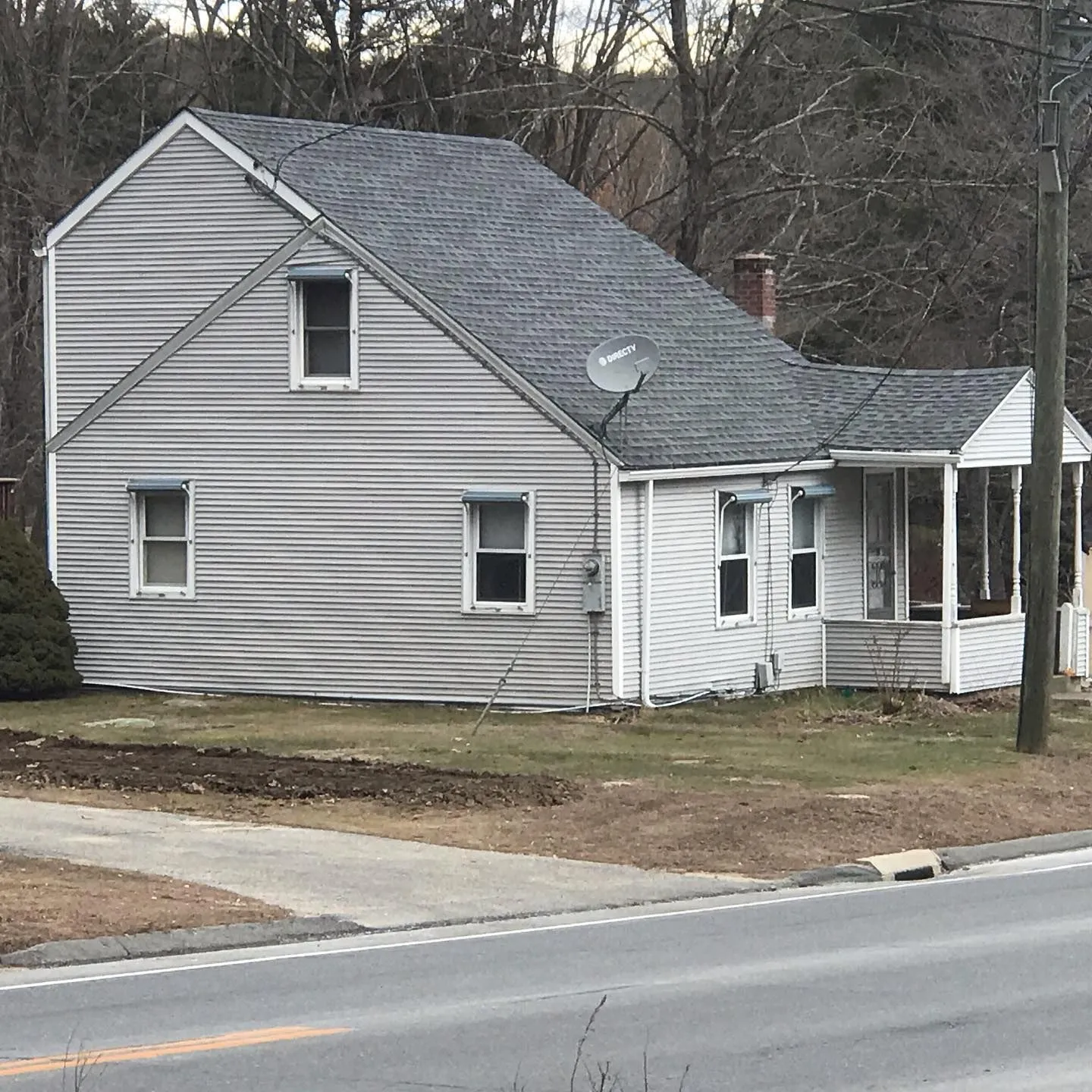 Gray-sided Cape house beside a rural road before renovation