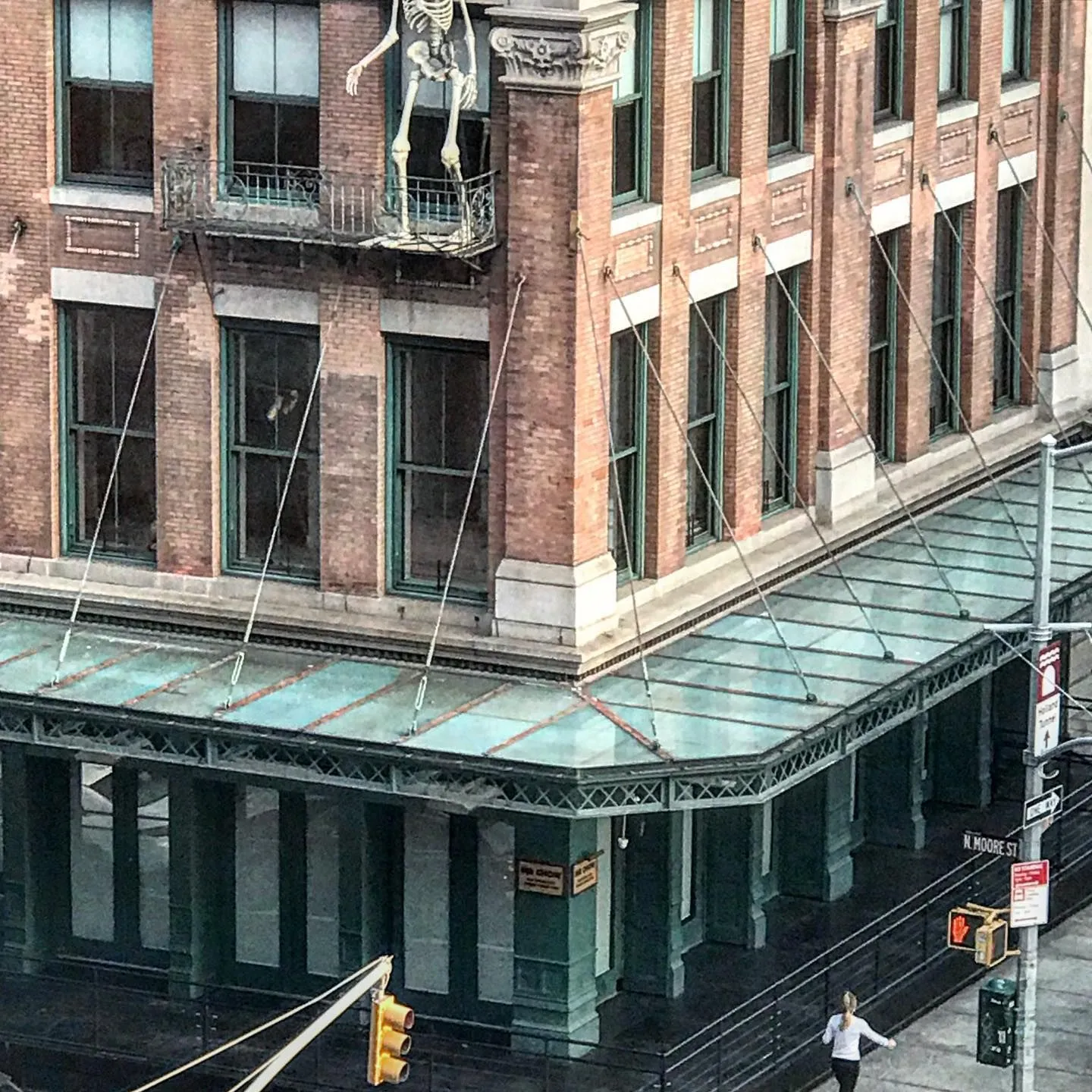 Cast-iron building corner with a green glass canopy and a skeleton sculpture above