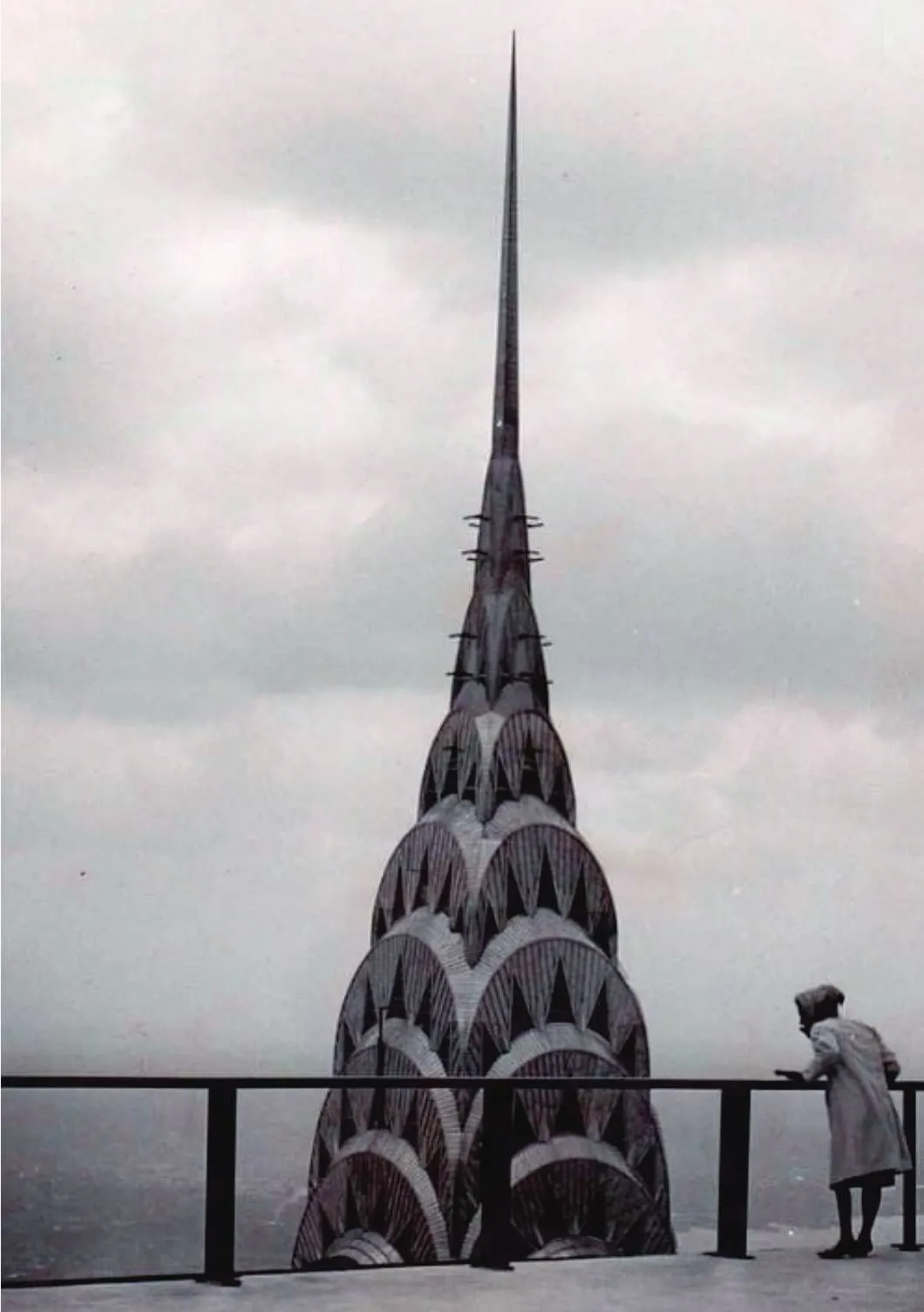 Chrysler Building crown seen from an observation deck with a visitor at the rail
