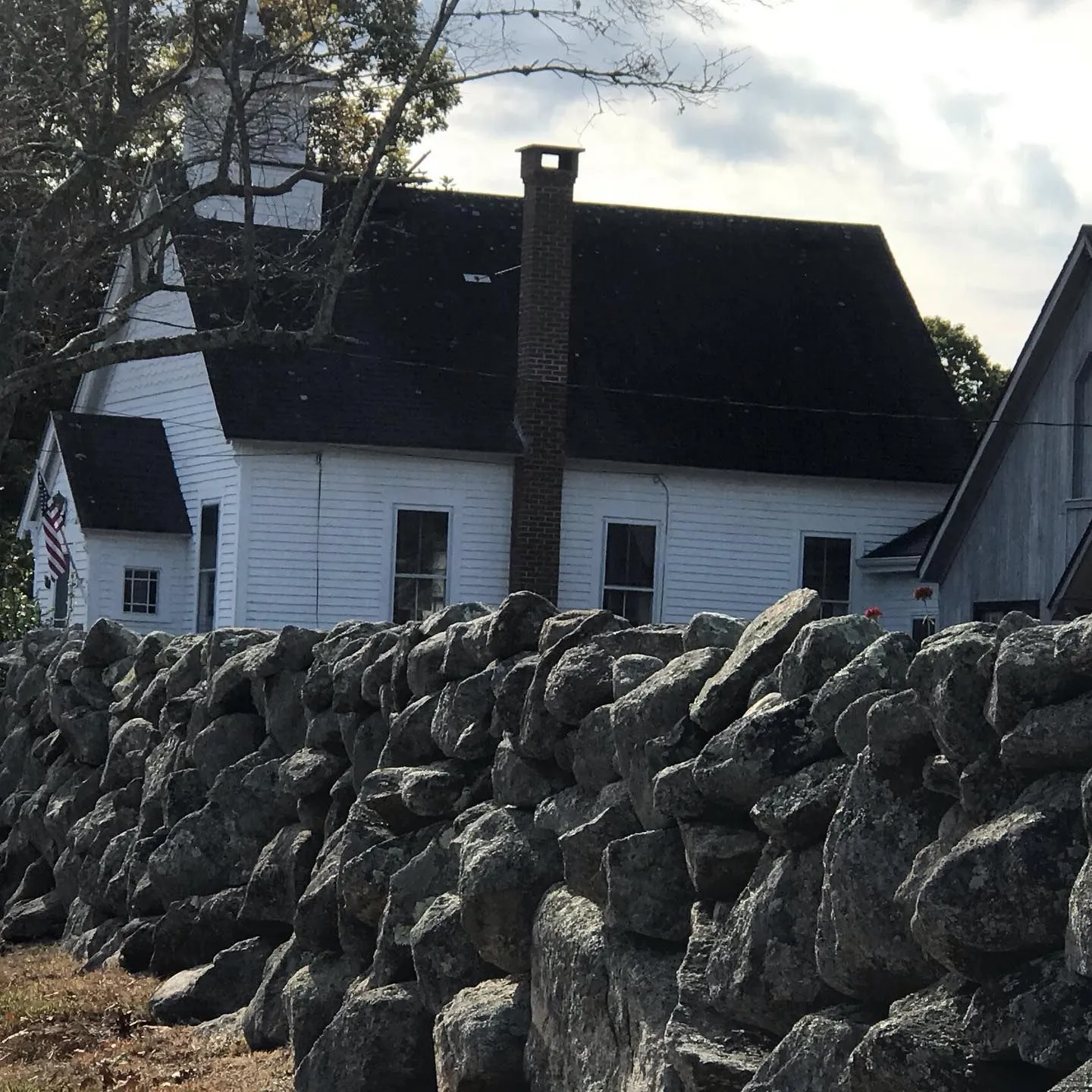 White clapboard church behind a New England fieldstone wall