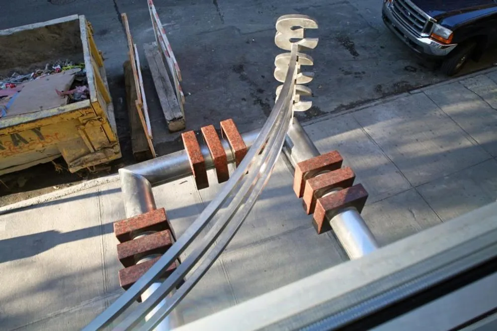 Overhead view of a curved steel railing with brick-clad posts above a sidewalk