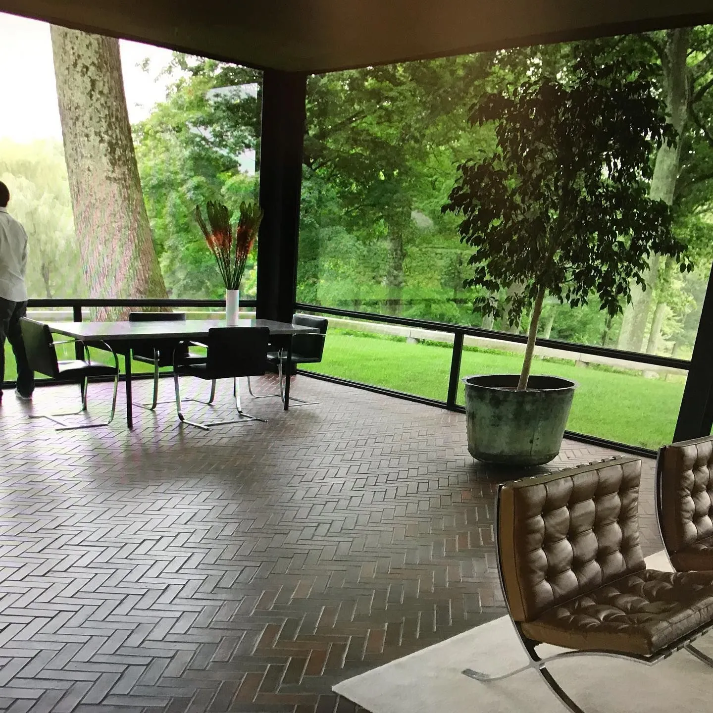 Barcelona chairs and dining table on a herringbone brick floor in Philip Johnson's Glass House
