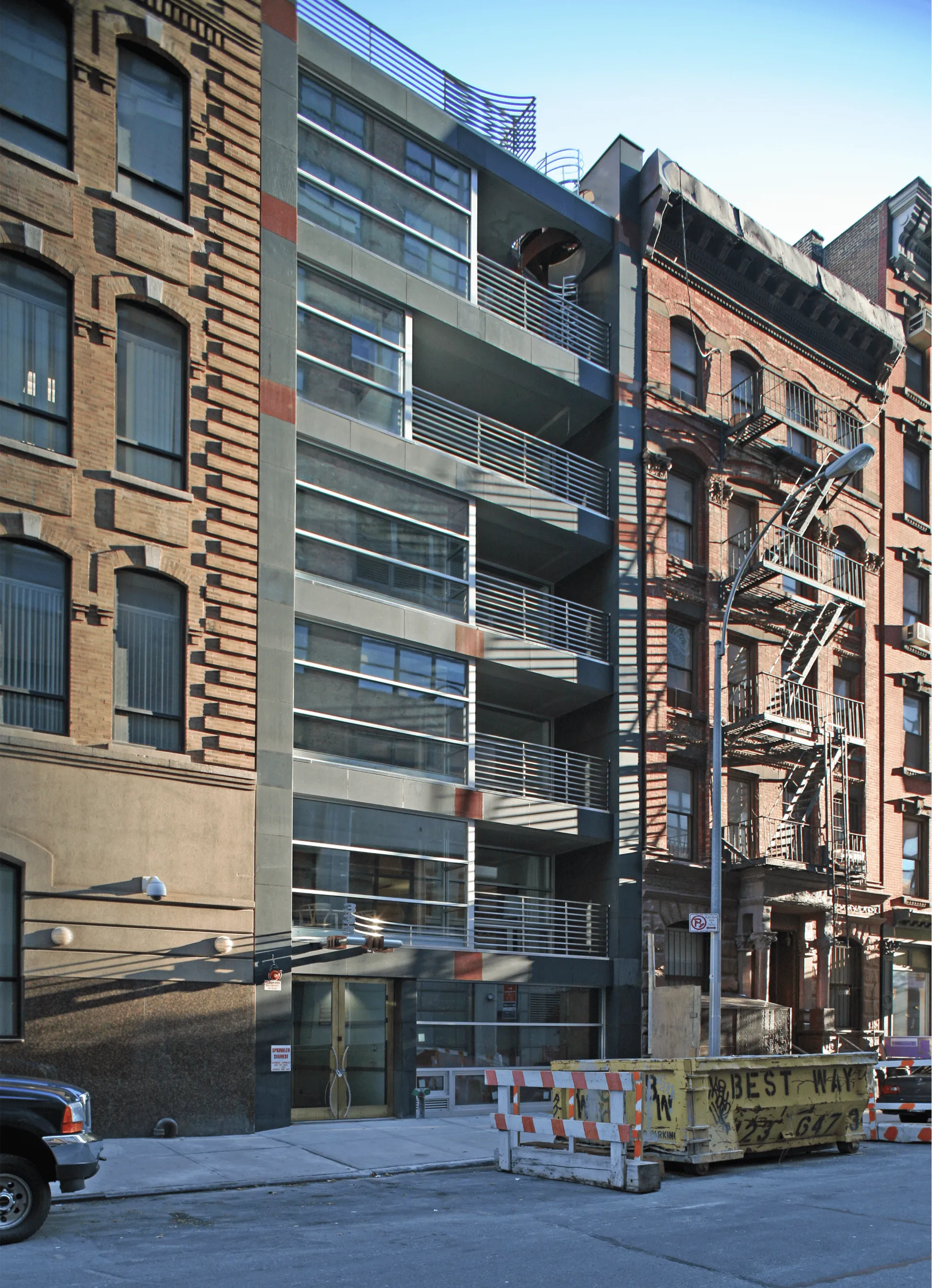 Glass and metal infill apartment building between brick tenements