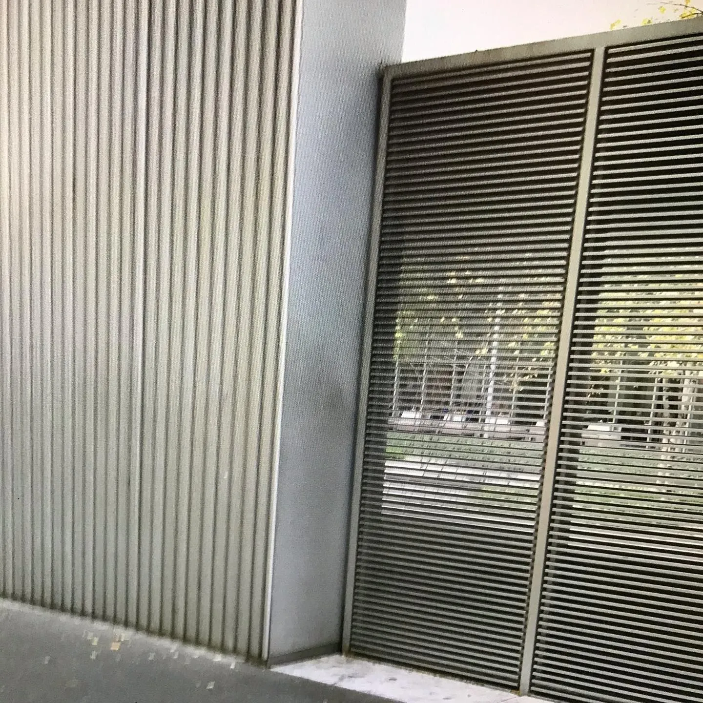 Horizontal metal louvers beside a ribbed white wall panel