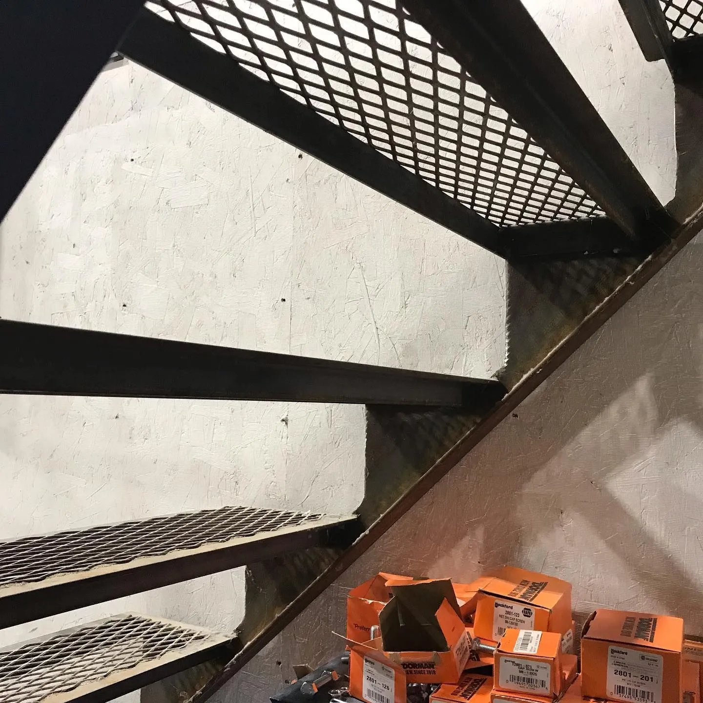 Steel mesh stair treads against a concrete wall during construction
