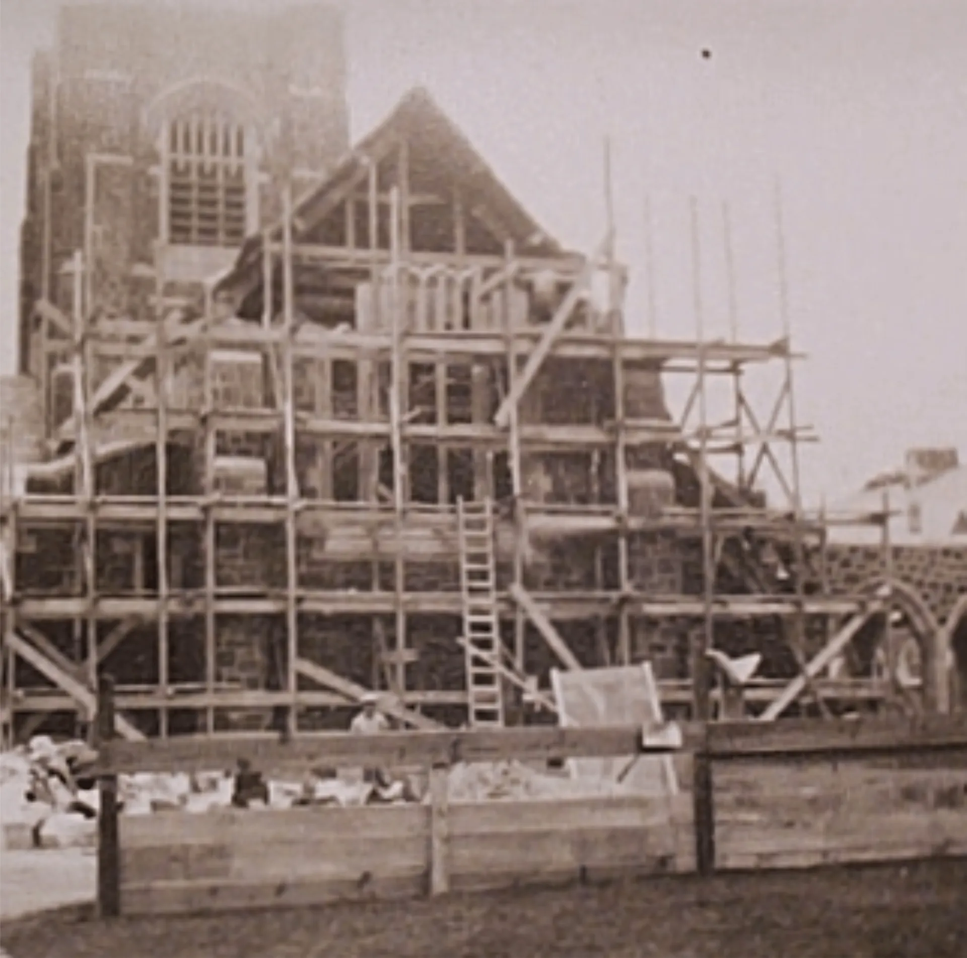 Archival photo of a stone church tower wrapped in timber scaffolding